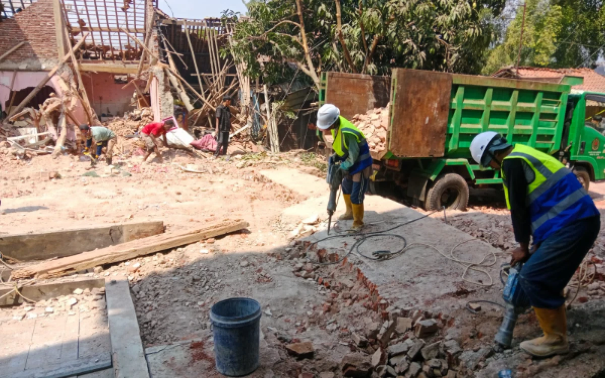 Foto Relawan bekerja keras menghancurkan reruntuhan yang tebal dengan alat breaker