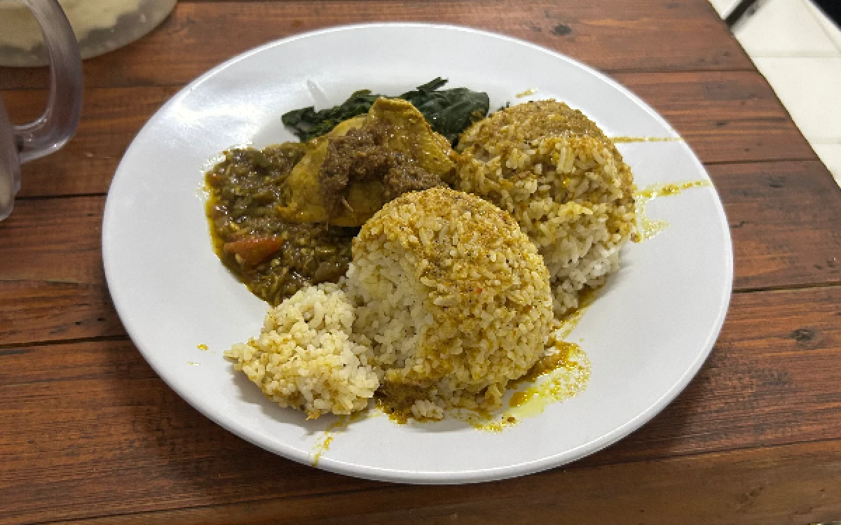 Foto Seporsi hidangan RM Padang Suku Jambak yang berisi nasi dengan kuah gulai kental, lauk berbumbu pekat, dan daun singkong di atas meja kayu, yang menjadi wujud konsistensi mempertahankan kekayaan rempah warisan keluarga. (Fabio Pratama/Ketik.com)