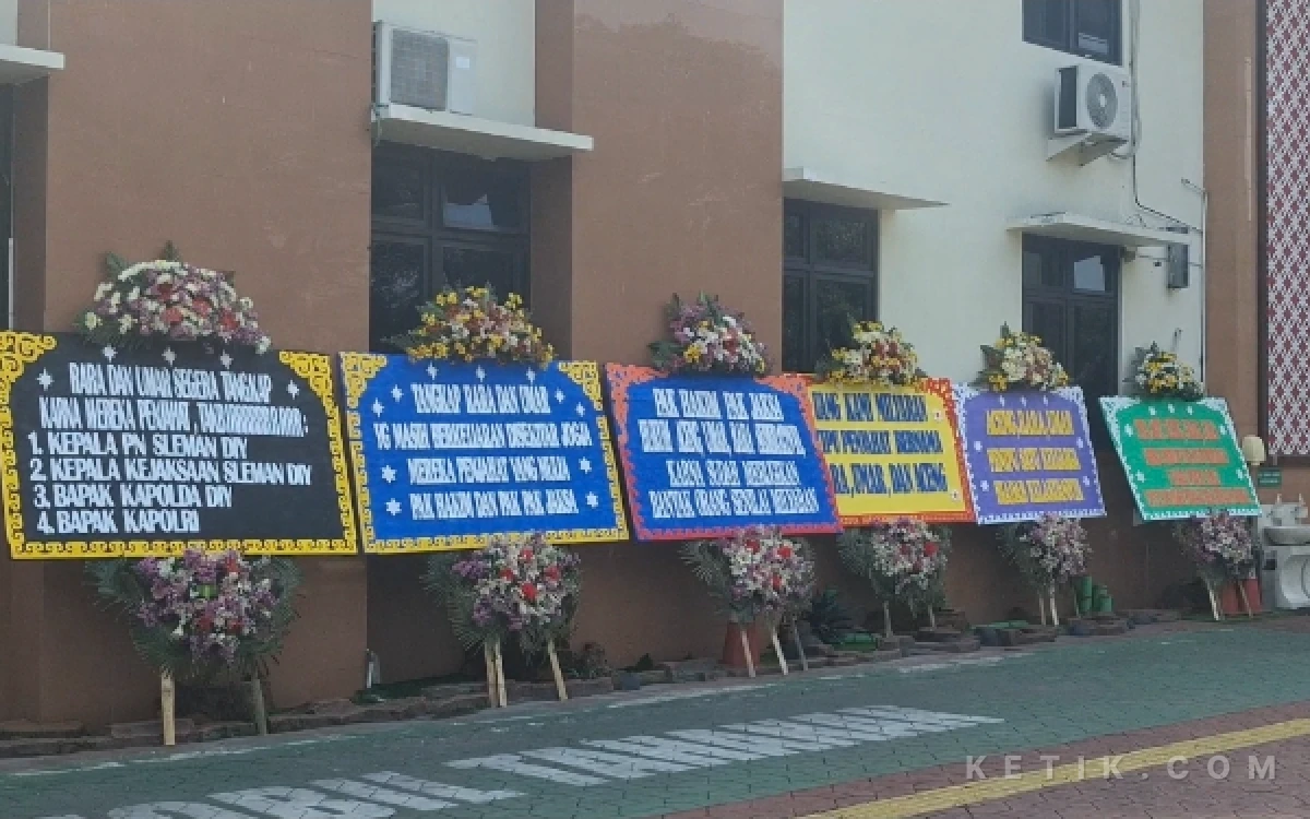 Foto Deretan karangan bunga berjejer memenuhi halaman depan PN Sleman, Kamis 18 Juni 2026. Karangan bunga tersebut berisi kecaman keras serta desakan kepada majelis hakim, jaksa, dan aparat kepolisian untuk mengusut tuntas kasus penipuan miliaran rupiah serta menghukum seberat-beratnya terdakwa Aceng Tata dan komplotannya yang telah merugikan banyak pedagang beras. (Foto: Fajar R/Ketik.com)