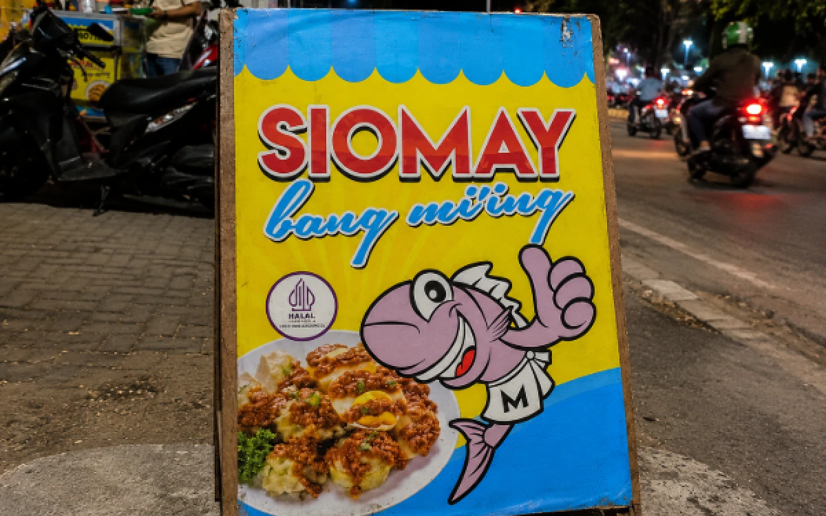 Foto Papan penanda Siomay Bang Mi'ing di Jalan Rungkut Madya, Surabaya. Eksis sejak 1985, kuliner legendaris ini terus menjadi primadona warga sekitar dan mahasiswa UPNVJT berkat harganya yang ramah di kantong, yakni mulai Rp1.500 per potong. (Foto: Ketik.com)