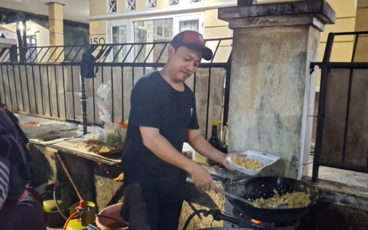 Foto Potret Pak Ferdi, penjual Nasi Goreng Mbah Darman, tengah mewadahi pesanan nasi goreng pelanggan. (Foto: Yasmin Farah Dhiya/ketik.com)