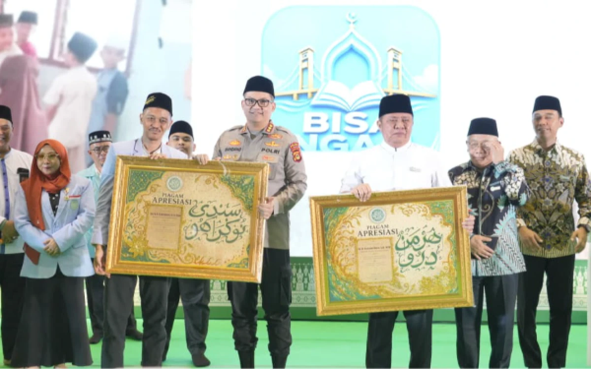 Foto Kabid Humas Polda Sumsel Kombes Pol. Nandang Mu'min Wijaya saat mendapatkan plakat apresiasi dalam rangkaian Tasyakuran 10.000 Santri Bebas Buta Aksara Al-Qur’an dan Wisuda Akbar 2026 di Palembang Sport and Convention Center (PSCC), Jalan Pom IX, Palembang, Senin 31 Agustus 2026. (Foto : Yola/Ketik.com)
