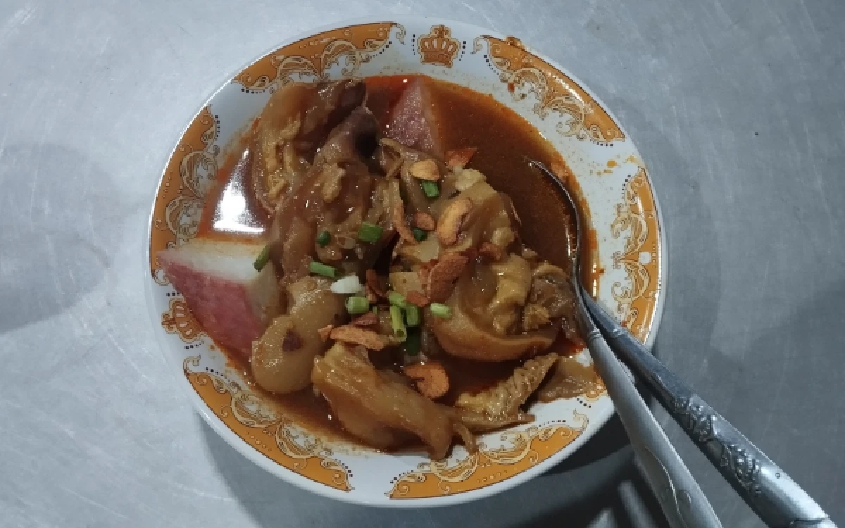 Foto Semangkuk lontong kikil khas Tahu Campur Lamongan Mas Chus dengan potongan kikil, lontong, dan kuah kental berwarna cokelat kemerahan, siap disajikan kepada pengunjung, pada Kamis, 20 Agustus 2026. (Rayyan Nabil Abrary/ketik.com)