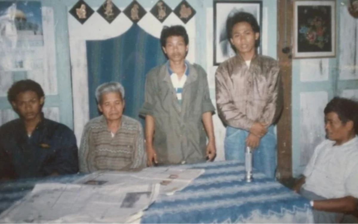 Foto Nampak Alm Mbah Maridjan berdampingan dengan Fajar R Jurnalis Ketik.com (paling kiri), 13 Februari 1993, sedang duduk santai di meja makan beralas taplak biru. Di atas meja, tampak lembaran koran yang sedang dibahas bersama, memperlihatkan bagaimana rumah beliau menjadi ruang diskusi yang hidup antara sang penjaga gunung dan para petualang muda. (Foto: Dok Fajar R/Ketik.com)