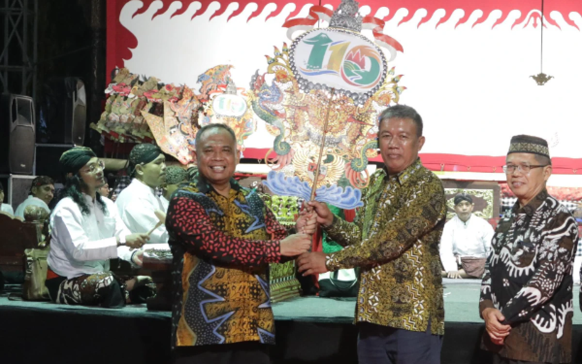 Foto Bupati Sleman Harda Kiswaya (kiri) menyerahkan gunungan kepada Kadis Kebudayaan Ishadi Zayid saat membuka pagelaran wayang kulit kolosal 15 Dalang di Lapangan Denggung, Sleman, Jumat malam, 15 Mei 2026. (Foto: Prokompim Slmn for Ketik.com)