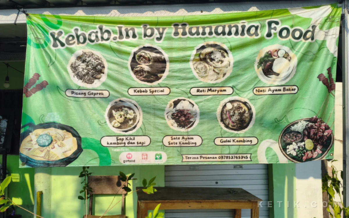 Foto Spanduk "Kebab In by Hanania Food" terpasang di depan warung, menampilkan menu tambahan kebab dan roti maryam berdampingan dengan sate serta sop kikil andalan di jalan Teluk Bone Utara, Surabaya pada Minggu, 16 Agustus 2026 (Muhammad Fathurrohman/Ketik.com)
