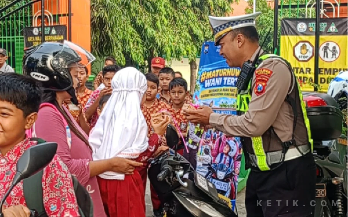 Foto Kanit Lantas Polsek Driyorejo, Ipda Aang Sutikno, Saat Berikan Kue Kepada Pengantar Sekolah Yang Tertib (Foto: Daniel Andayawan/Ketik.com)
